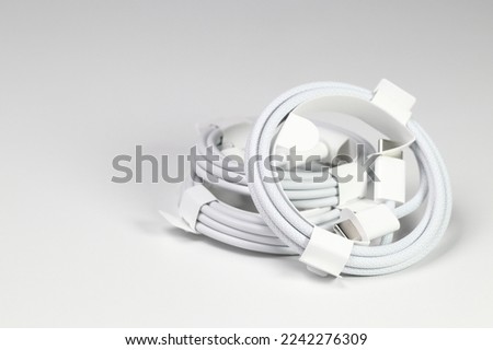 New white USB type charger cable, compatible for many devices, wrapped in a spiral shape, isolated on white background.