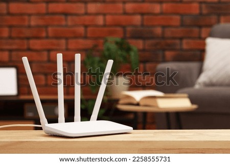 New white Wi-Fi router on wooden table indoors. Space for text
