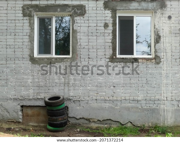 New windows in the slum. Old house. Shack.\
Stacked car tires\
