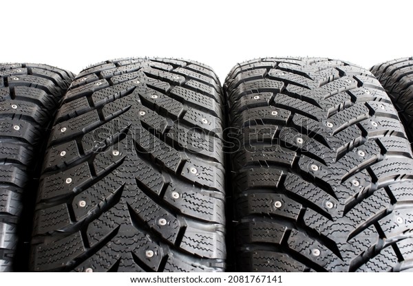 New winter car\
tires with spikes on a white background close-up. Tire tread. Set\
of winter car tires. defocus\
