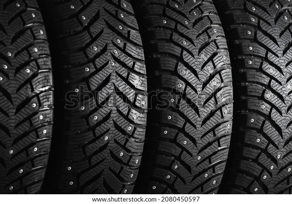 New winter tires with spikes close-up\
on a black background. Set of winter car tires\
