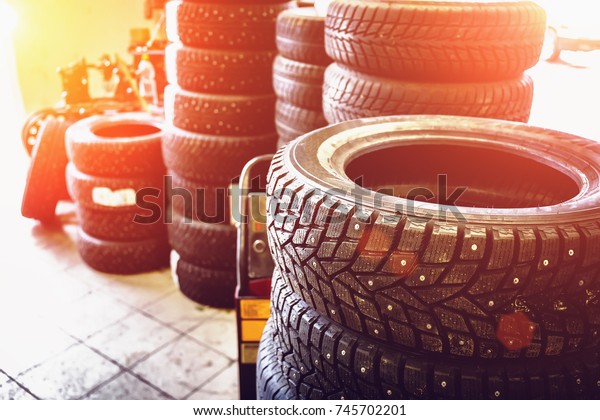 New winter tires\
in stacks inside automotive garage service - changing wheels or\
tires, sunlight effect,\
toned