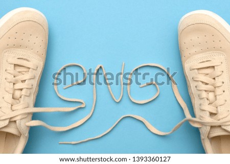 New women sneakers with laces in eng text abbreviation. Electronic news gathering. Flat lay on blue background.