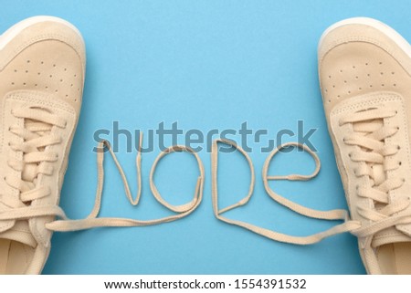 New women sneakers with laces in node text. Flat lay on blue background.