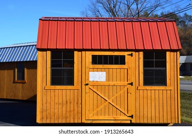 New Wood Storage Shed On Display. The Shed Is Used As Outdoor Storage And Commonly Located In Home Backyard. Red Metal Roof