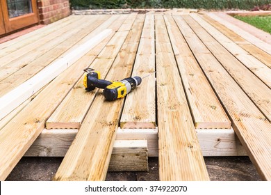 A new wooden, timber deck being constructed. it is partially completed. a drill can be seen on the decking. - Shutterstock ID 374922070