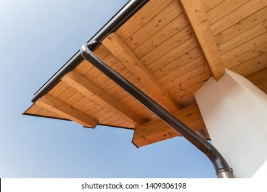 New wooden warm ecological house roof with steel gutter rain system. Professional construction and drainage pipes installation. Eco materials.
