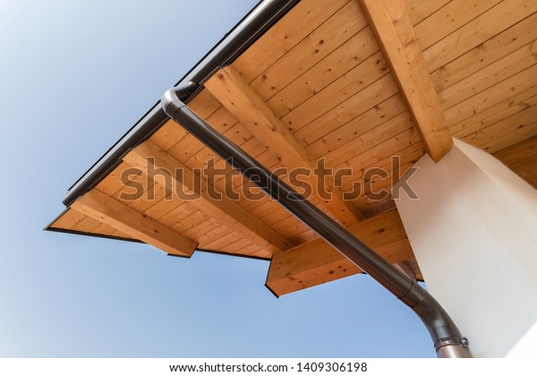 New wooden warm ecological house roof with\
steel gutter rain system. Professional construction and drainage\
pipes installation. Eco\
materials.\
