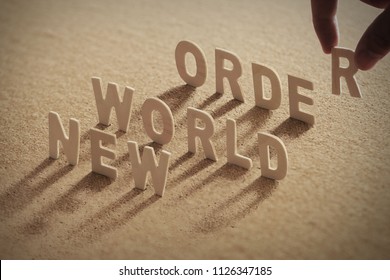 NEW WORLD ORDER Wood Word On Compressed Or Corkboard With Human's Finger At T Letter.
