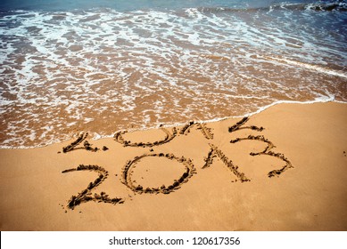 New Year 2013 is coming concept - inscription 2012 and 2013 on a beach sand, the wave is covering digits 2012