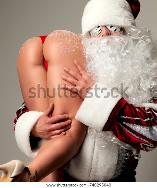 New year 2018 christmas concept. Bad santa claus in snow flakes sunglasses hold young sexy naked ass woman with long legs and high hills