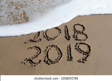 New Year 2019 is coming concept - inscription 2018 and 2019 on a beach sand, the wave is starting to cover the digits 2018