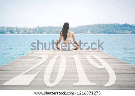 New year 2019 concept, Happy woman with white bikini practice yoga and meditation on wooden bridge in tropical beach, Thailand