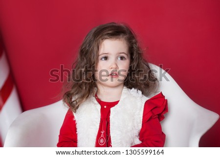 New Year 2020! Christmas, holidays and childhood concept. Merry Christmas and happy holidays! Closeup portrait. Little curly girl on an isolated red background. Portrait baby girl. Birthday, holiday