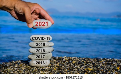 New Year 2021 Is Coming Concept. Covid Year Change To 2021 Background. Turn Of Old Year Concept. Happy New Year 2021 Replace Corona. New Hopes, Excitement With 2021. Man Adding Stone To Pebble Tower.