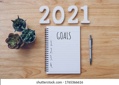 New year 2021 goals list. Office desk table with notebooks and pancil with pot plant.