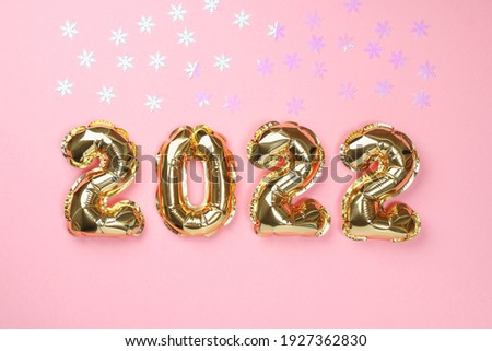 New Year 2022. Foil balloons numbers 2022 on a pink background. New Year Christmas.