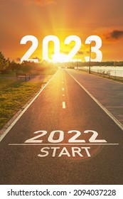 New Year 2022 Start Concept. The Numbers 2022 And 2023 Years Is Written On The Asphalt On The Empty Sports Path In The Bright Rays Of The Sun. Motivational Concept For Vision And Action On Future