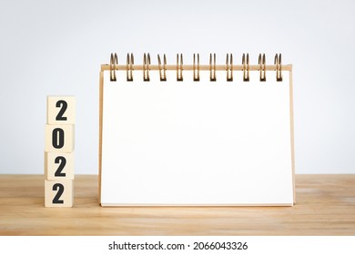 New year 2022 for new start with cubes wooden on table background, space for text on notepad mockup calendar and start up concept.