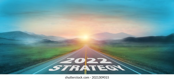 New year 2022 or start straight concept. Text 2022 and strategy written on the road with sunrise background. Concept of goal and challenge or career path, success, opportunity, change and hope.