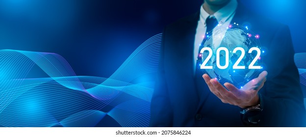 New year 2022,future technology,Business development and growth concept.Smart businessman holding digital earth and word 2022 on dark blue background.Development to success and motivation