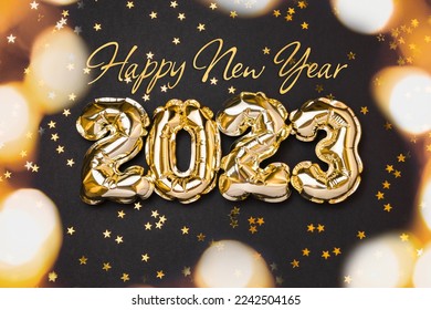 New year 2023 balloon celebration card. Gold foil helium balloon number 2023 and gold confetti stars isolated on black background. Flat lay, merry christmas, happy holidays congratulations.
