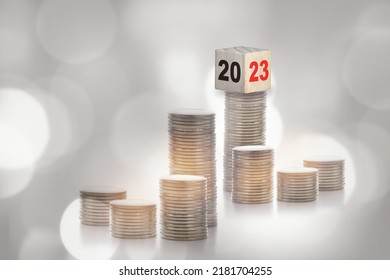 New Year 2023 On Cube On Stack Of Coins On Abstract Background. Saving With Return On Investment Concept And Sustainable Economic Growth Idea