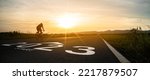 New year 2023 or start straight and beginning concept.silhouette of Blurry Man ride on bike and word 2023 start written on the road at sunset.Concept of challenge or career path,business strategy.
