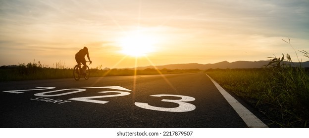 New year 2023 or start straight and beginning concept.silhouette of Blurry Man ride on bike and word 2023 start written on the road at sunset.Concept of challenge or career path,business strategy. - Shutterstock ID 2217879507