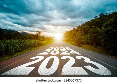 New year 2023 or straight forward concept. Text year 2023, 2024, 2025 written on the road in the middle of asphalt road with at sunset. Concept of planning, goal, challenge, new year resolution.