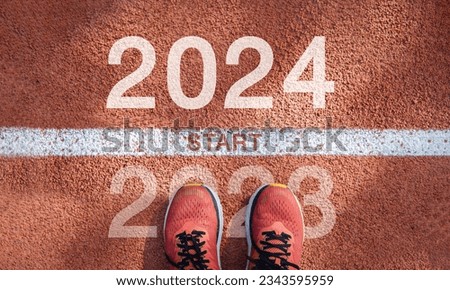 New year 2024 concept, beginning of success. Text 2024 written on asphalt road and male runner preparing for the new year. Concept of challenge or career path and change.