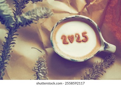 New Year 2025 celebrated coffee cup with number 2025 over frothy surface flat lay on brown crumpled paper background with dried pine branches. Holidays food art theme. (top view, selective focus) - Powered by Shutterstock