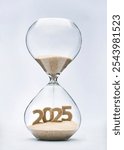 New Year 2025 concept with hourglass falling sand taking the shape of a 2025