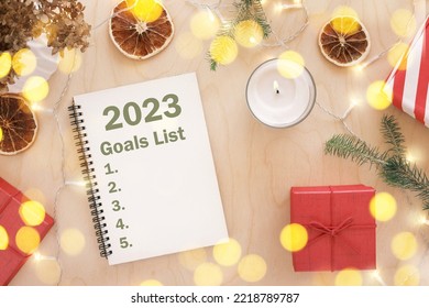 New Year Aims. 2023 To Do List writing. Writing in Empty Notebook at Wood Table with Christmas Decor. Top view. Creating Goal List, Resolutions. New Life, Start Up, Beginning Concept. Business ideas