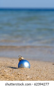 New Year At The Beach! Christmas Ornaments Standing In The Sand Near The Water!