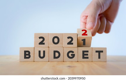 New year business plan concept in  2022. Male hand flips wooden cube and changes the inscription "BUDGET 20201" to "BUDGET 2022" with white  background, copy space. Use for banner and presentation. - Shutterstock ID 2039970950