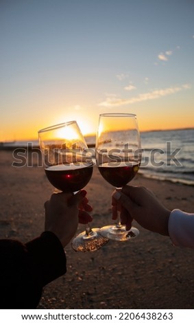 New year celebration during sunset on the beach. Cheers with red wine