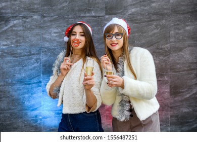 New Year celebration. Two happy women with champagne glasses posing on abstract background