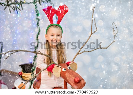 New Year and Christmas 2018. A beautiful girl with gloves on a Christmas deer laughs in the horns of a deer.