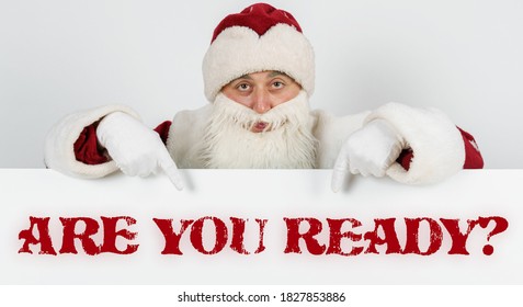 New Year and Christmas concept. Santa Claus points his fingers at the board with the text -ARE YOU READY
