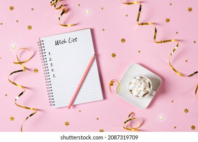 New Year, Christmas Or Holiday Wish List Concept. Notepad, Golden Tinsel, And A Cup Of Hot Chocolate With Marshmallows Isolated On Pink Background. Banner With Copy Space