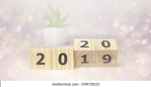 New Year concept from 2019 to 2020. Business and design concept - surreal abstract geometric floating wooden cube with word 2020 2019 concept on wood floor and christmas background