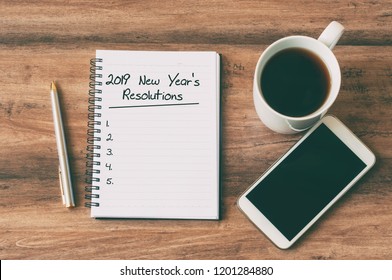 New year Concept - 2019 number and text on notepad. Smartphone, pen and cup of copy background. 