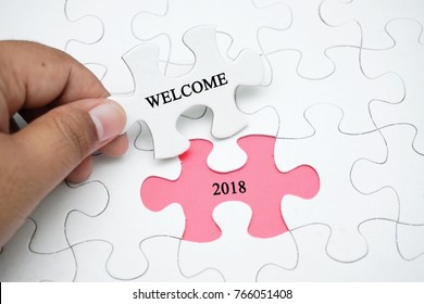 New Year Concept. Hand hold piece of puzzle with word Welcome and missing puzzle with a word 2018. - Shutterstock ID 766051408