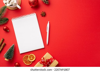 New Year concept. Top view photo of notepad pen red baubles fir branch craft paper giftbox cup of cocoa and dried citrus slices on isolated red background with blank space - Powered by Shutterstock