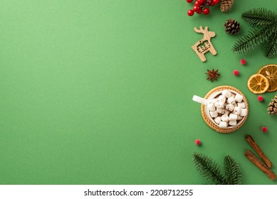 New Year concept. Top view photo of reindeer wood ornament spruce branches pine cones mug of cocoa with marshmallow mistletoe cinnamon dried orange slices on isolated green background with copyspace - Powered by Shutterstock