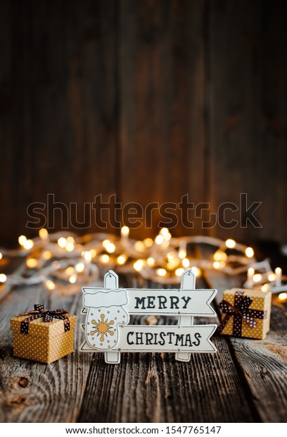 New\
year decoration and background for greetings with free space for\
text. Inscription with congratulations on the background of\
Christmas trees and lights bokeh on a wooden.\
2020