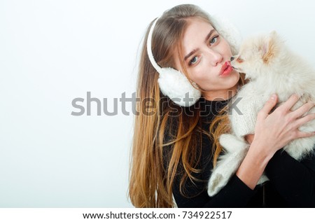 New year of dog and winter holiday celebration. Xmas party and vacation. Dog in hand of woman on white background. Girl with happy face in gloves and ears. Woman with small dog of Pomeranian Spitz.