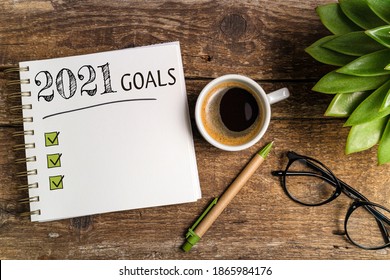 New year goals 2021 on desk. 2021 goals list with notebook, coffee cup, plant on wooden table. Resolutions, plan, goals, checklist, idea concept. New Year 2021 template, copy space - Shutterstock ID 1865984176