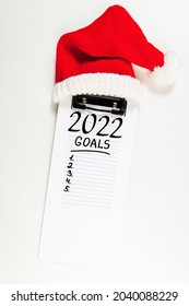 New Year Goals 2022 On Desk. 2022 Resolutions With Notebook And Santa Hat On White Background. Goals, Plan, Strategy, Change, Idea Concept. Copy Space